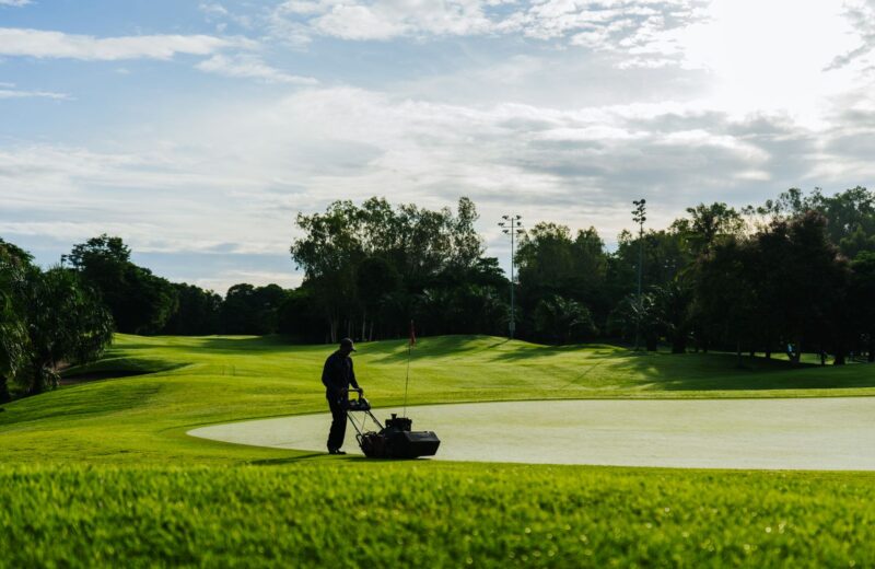 A greenkeeper mowing a green with a walk-behind mower