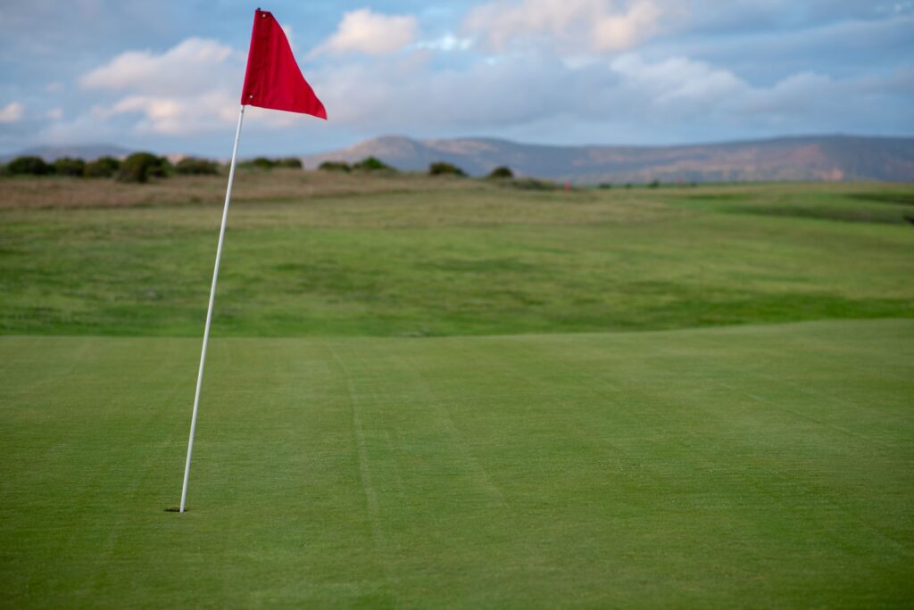 A red flag on a green under a clear blue sky