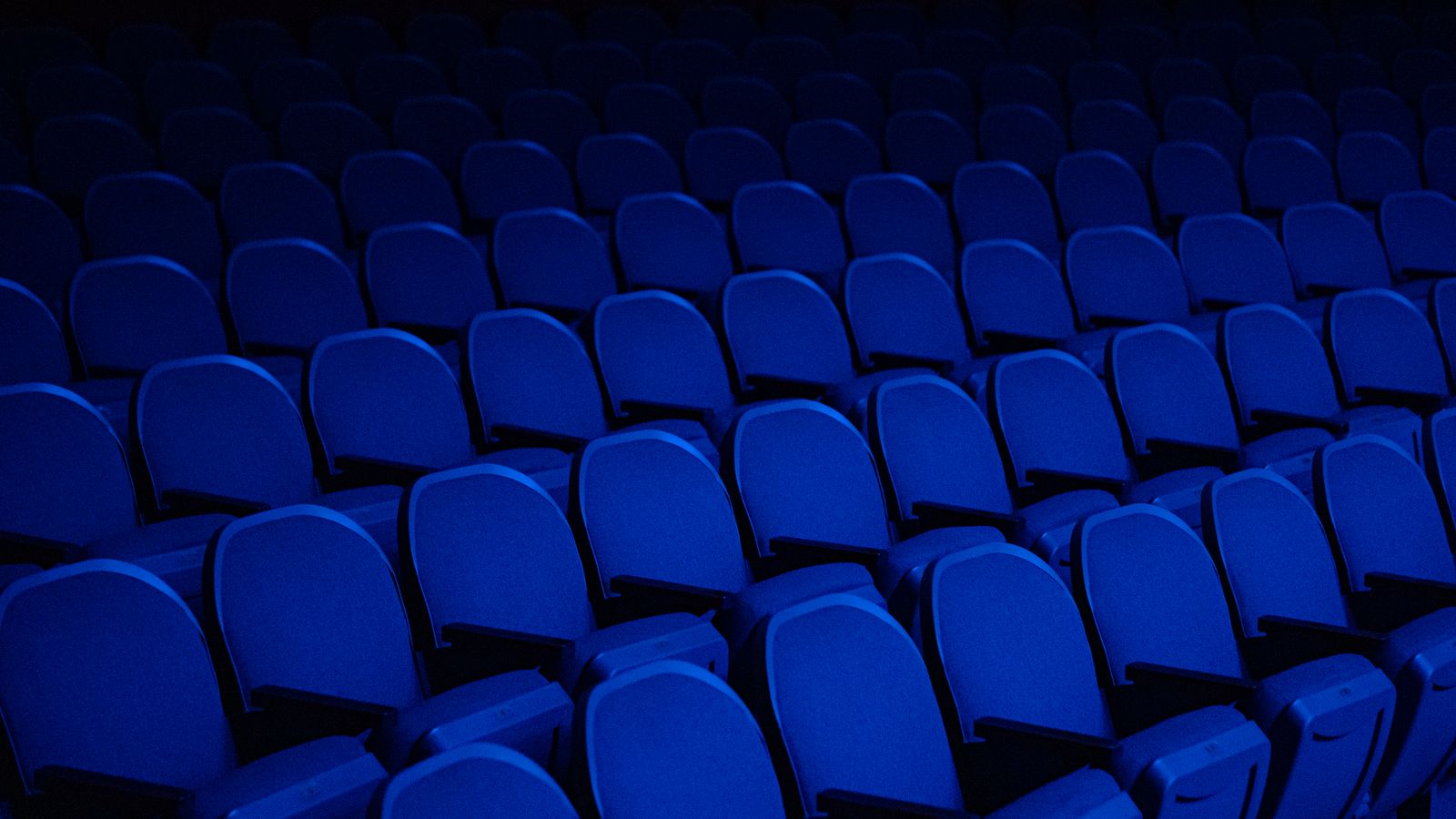 Rows of empty theatre seats in deep blue light