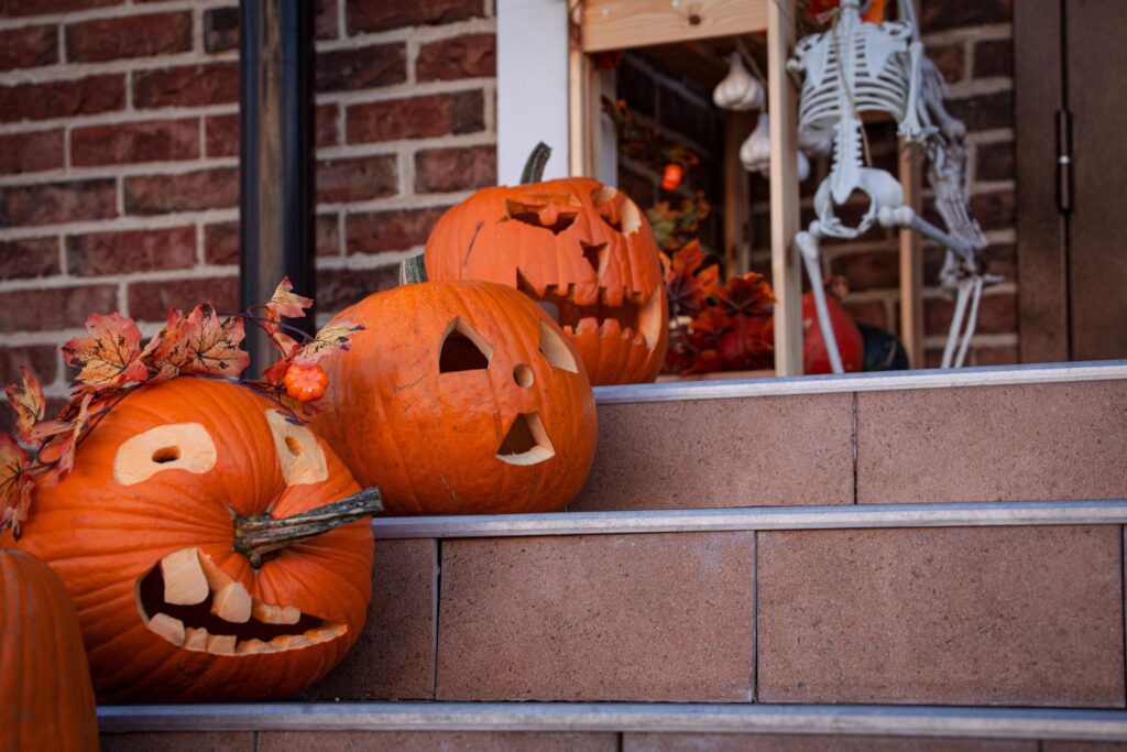Carved pumpkins and a plastic skeleton on the brick steps of a front door