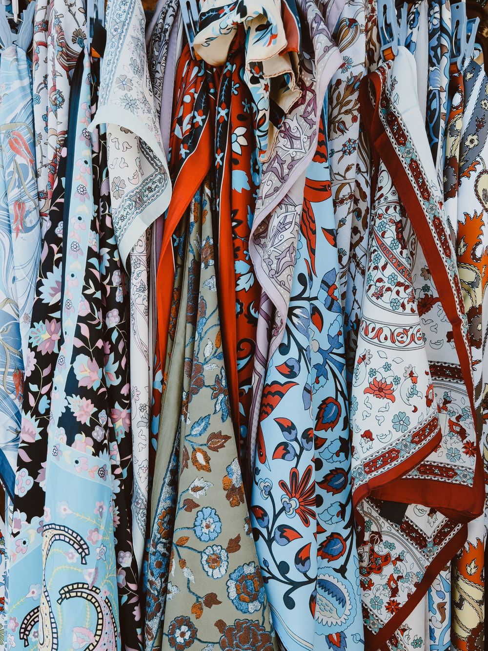 Rows of printed shawls in blue, orange and cream hanging side by side