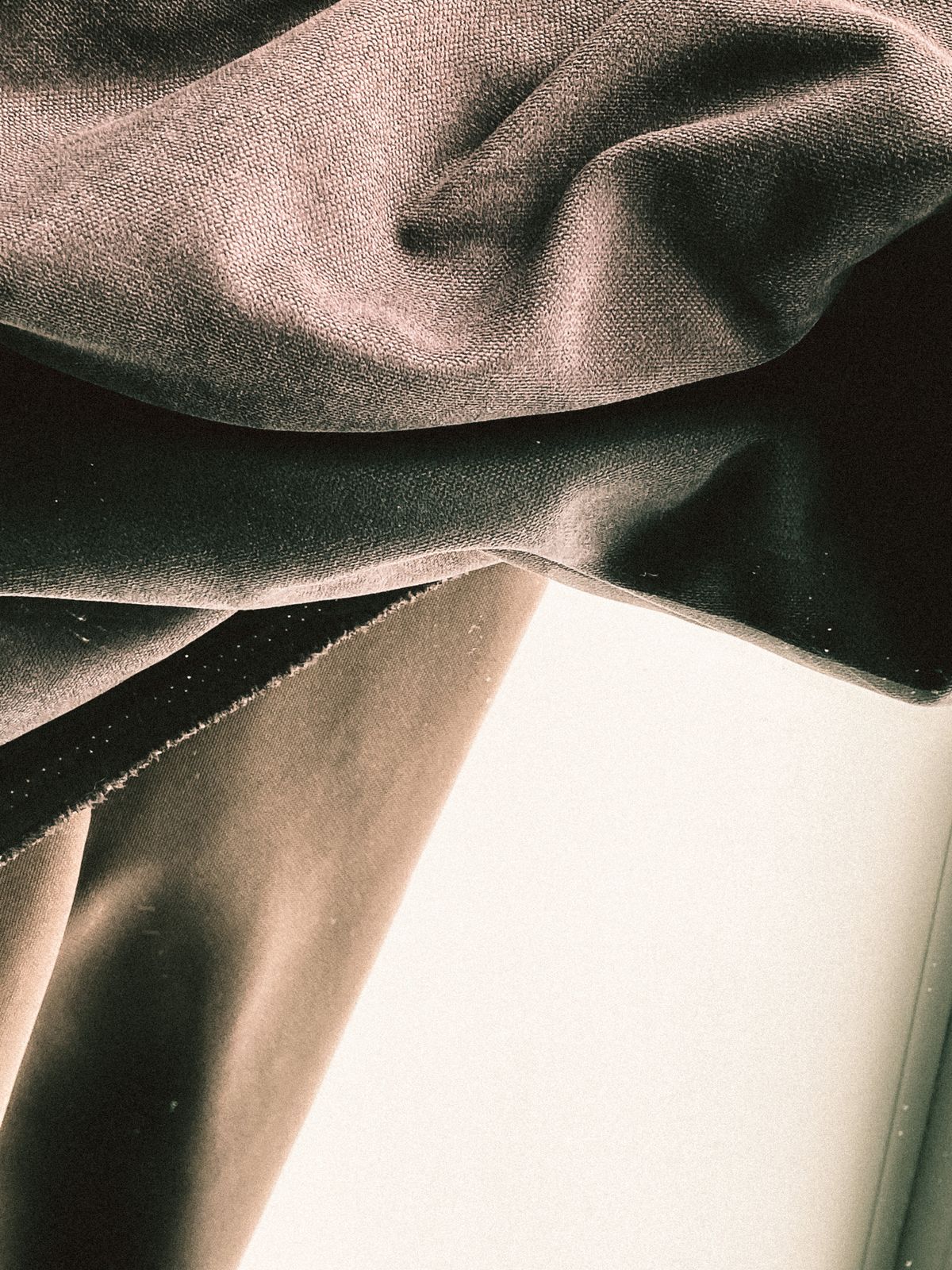 Soft draped fabric in pale neutral tones, folded in front of a mirror