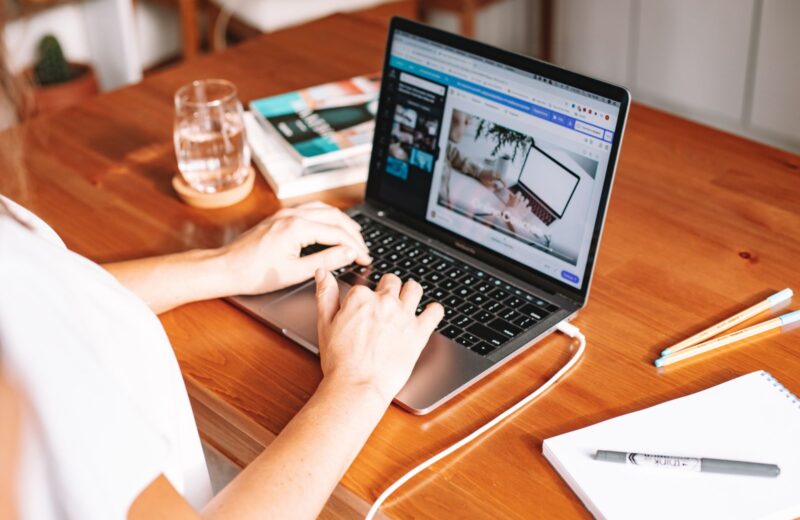 Hands typing on a laptop on a wooden table