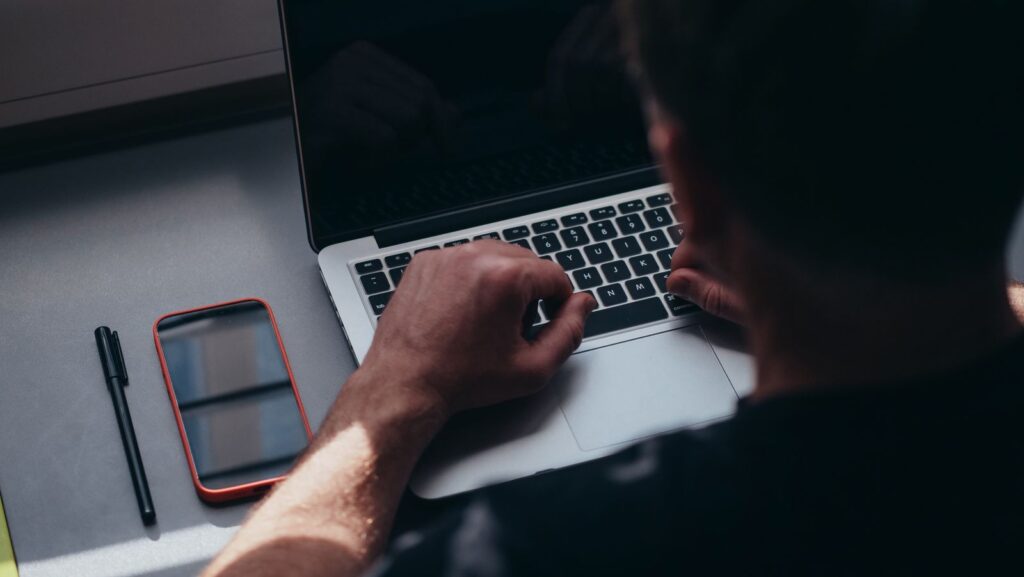 Person working on a laptop with a phone on the table