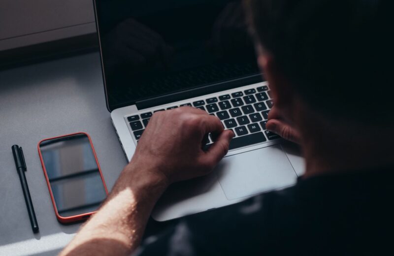 Person working on a laptop with a phone on the table