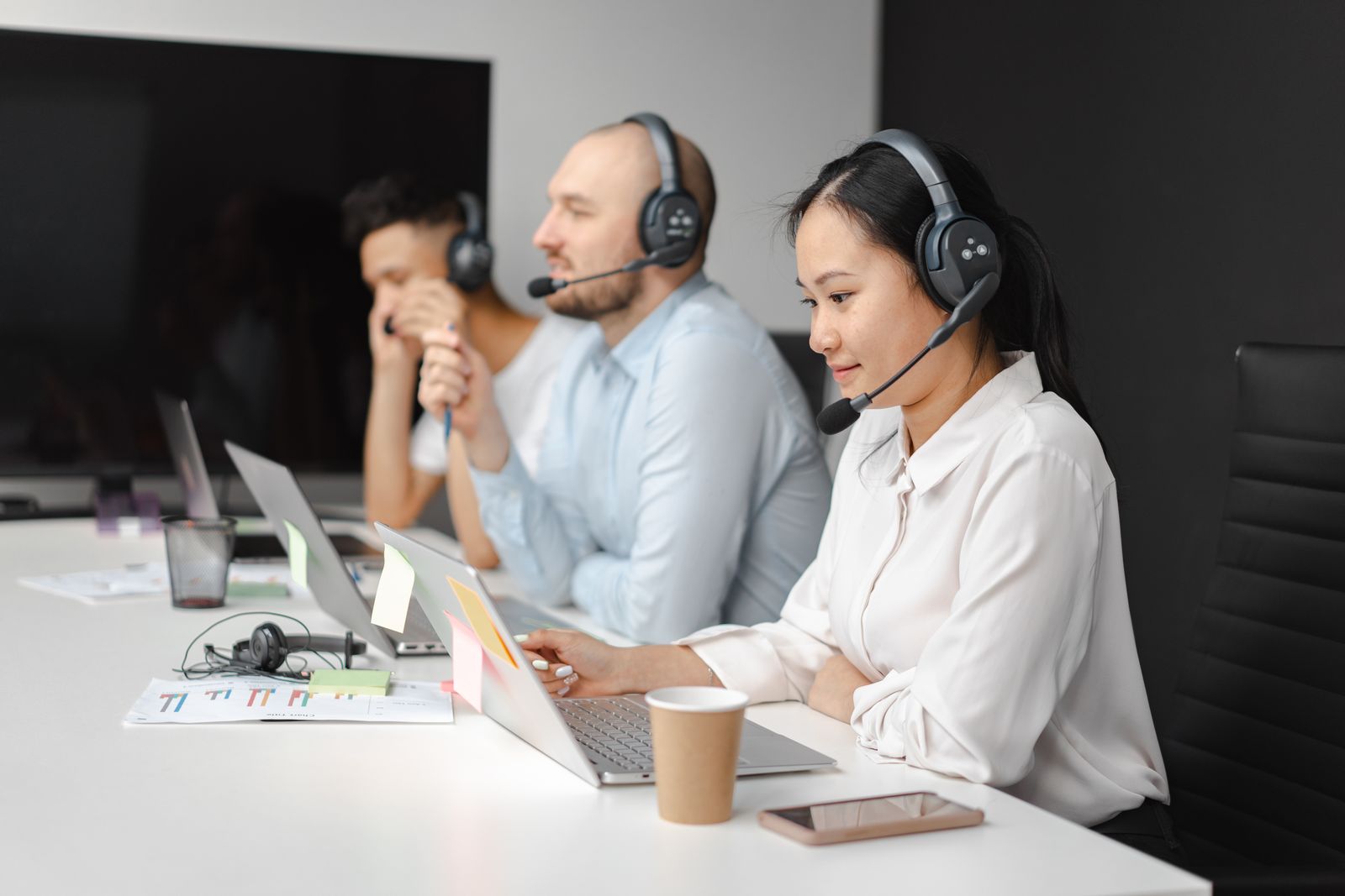 Three support staff with headsets answering customers at their laptops