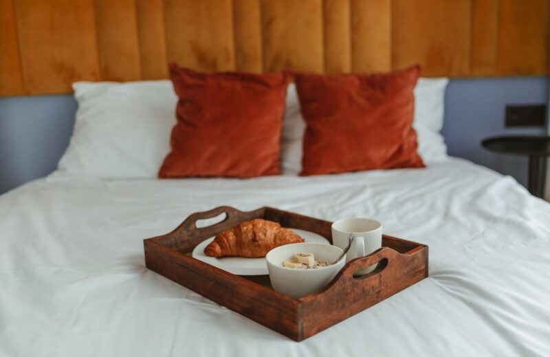 A breakfast tray with croissants and coffee on a made bed