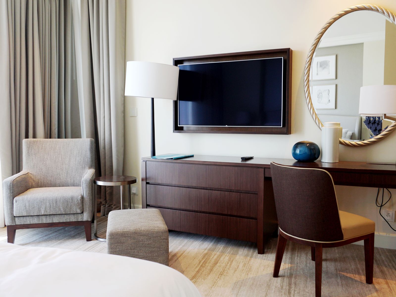 The sitting area of a suite with an armchair, a desk and a tall lamp