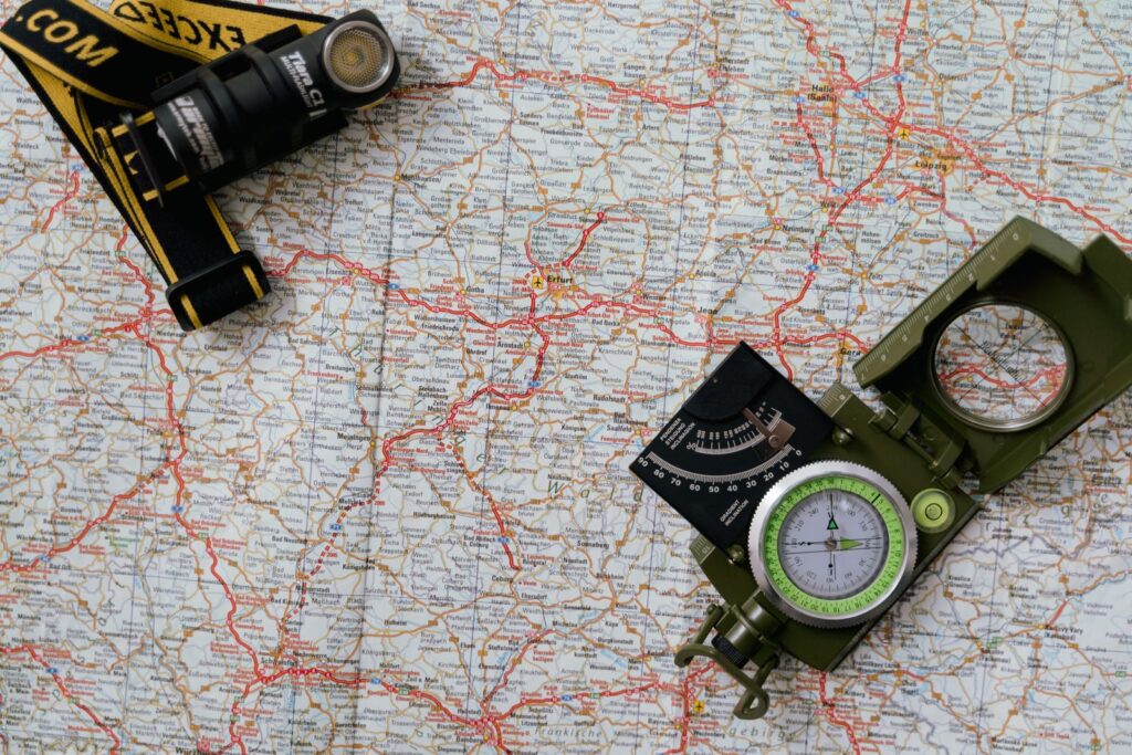 A paper map with a compass and a torch laid on top