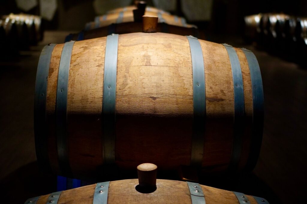Oak wine barrels in a dark cellar, one lit by a beam of light