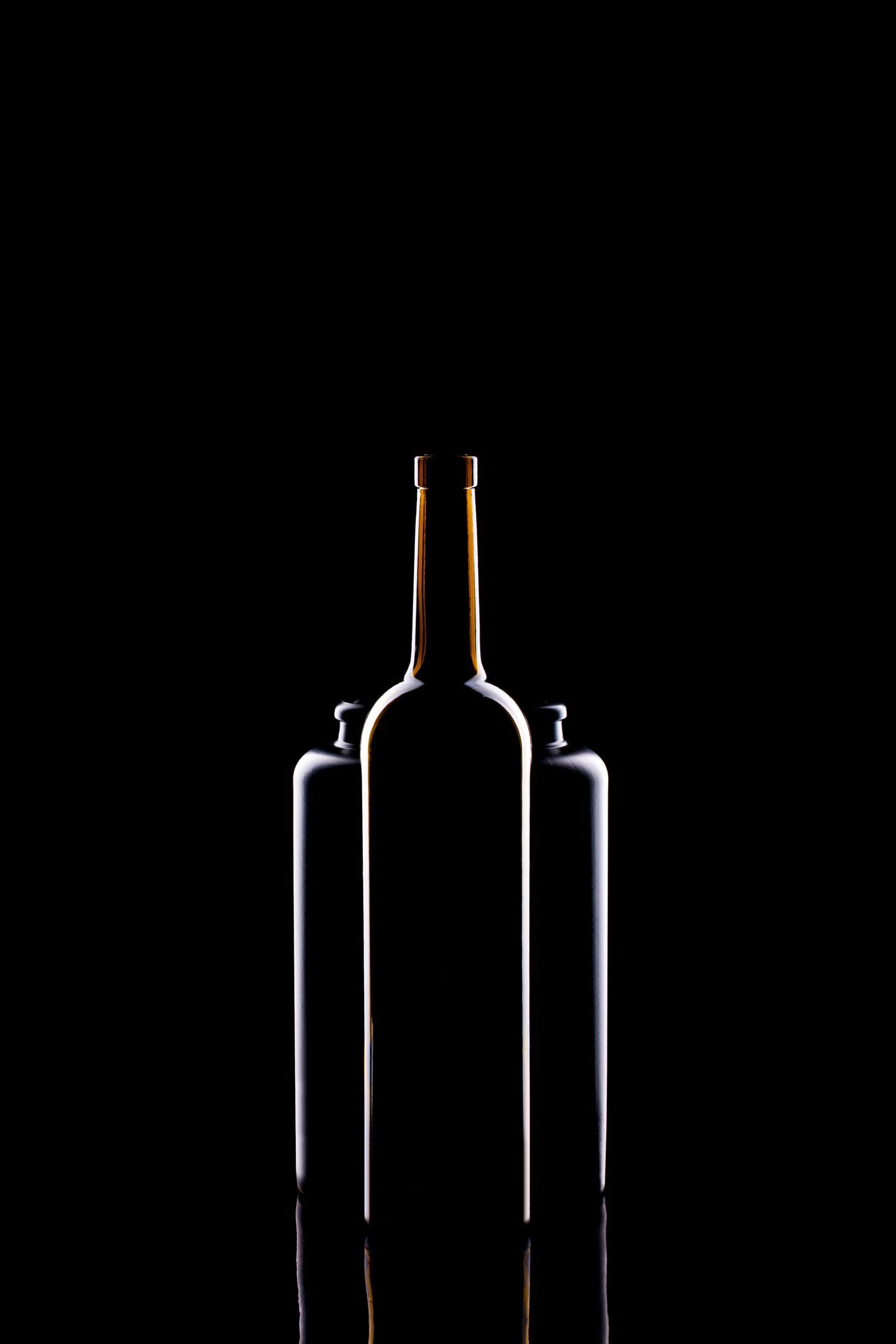 The outline of a wine bottle traced by thin light on a black background