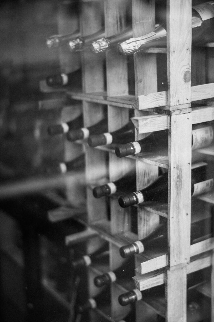 Black and white photo of bottles lying in a wooden wine rack