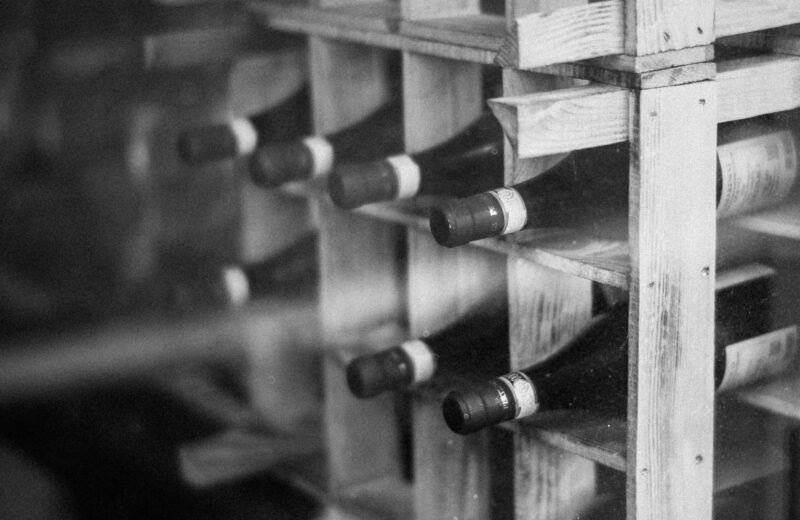 Black and white photo of bottles lying in a wooden wine rack