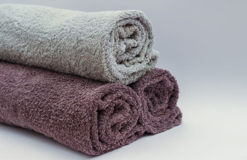 Rolled bath towels in grey and plum stacked together