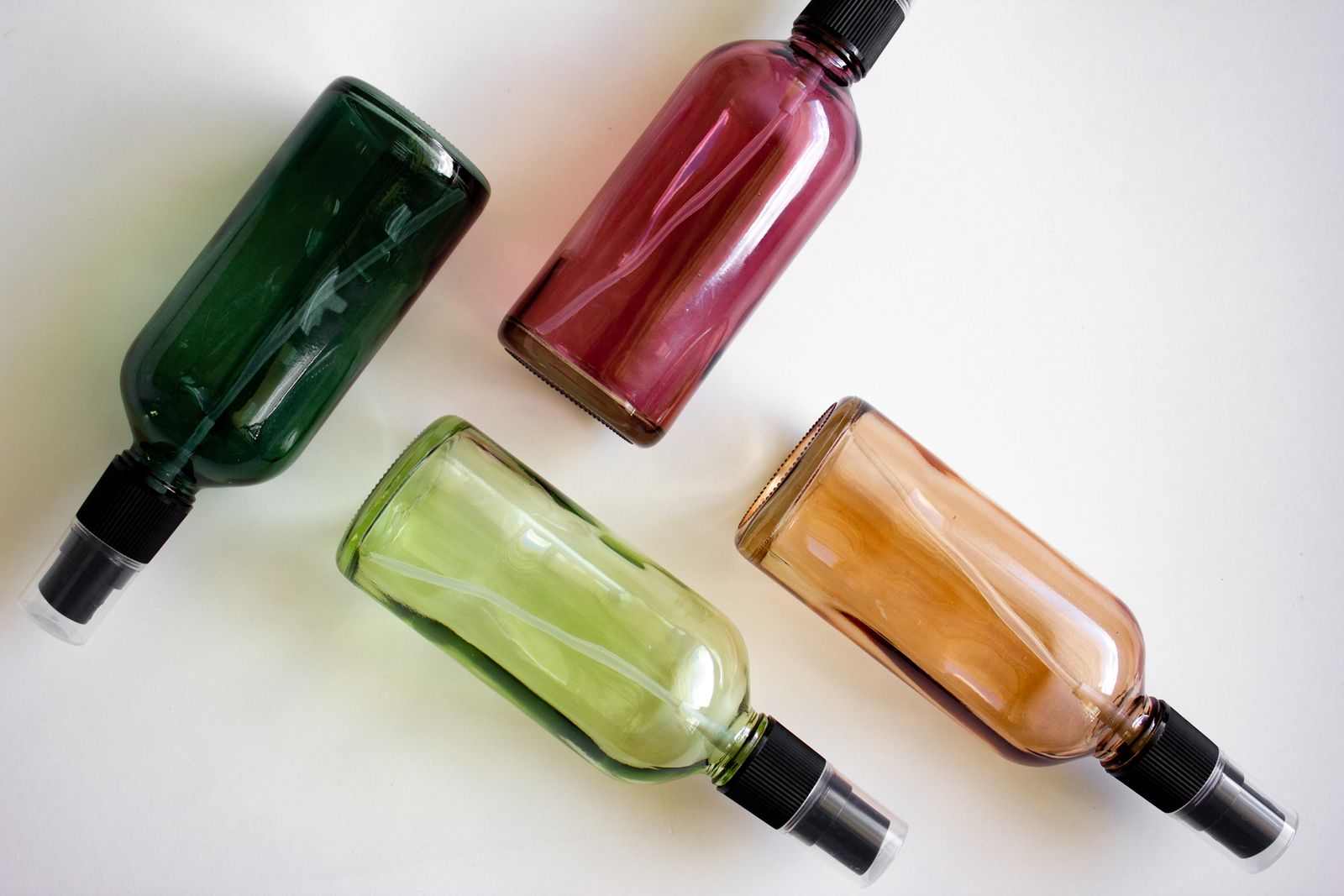 Four glass spray bottles filled with cleaning liquids