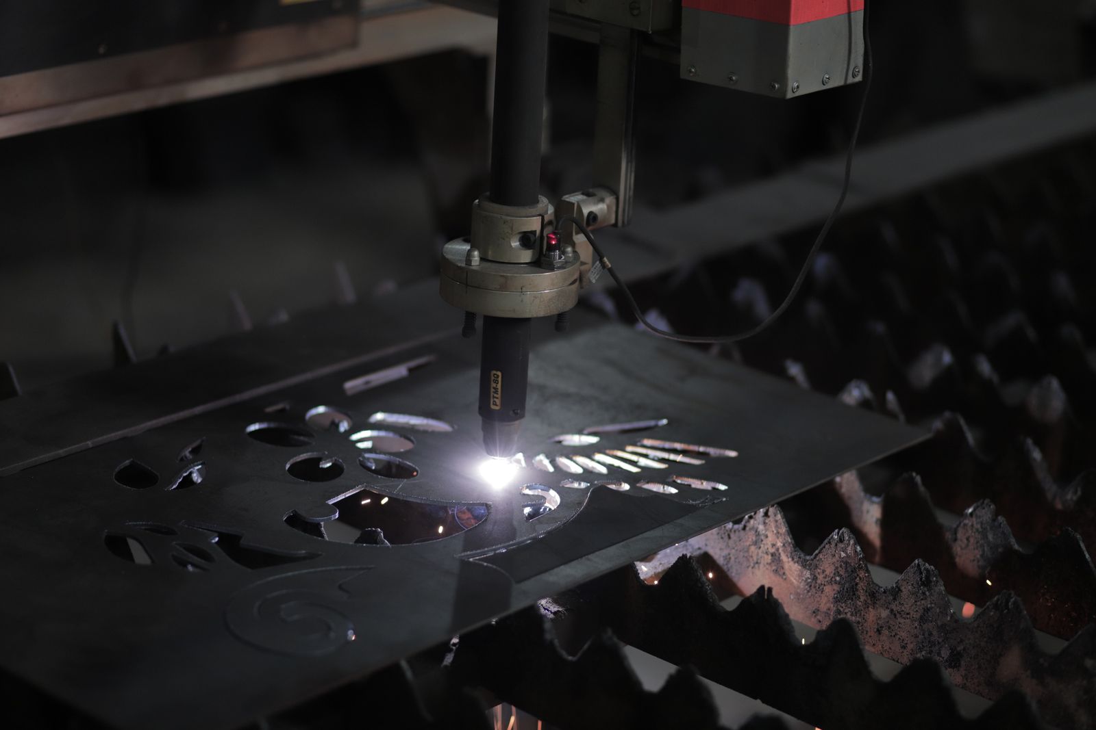 Cutting head tracing a shape in a steel sheet with a bright spark