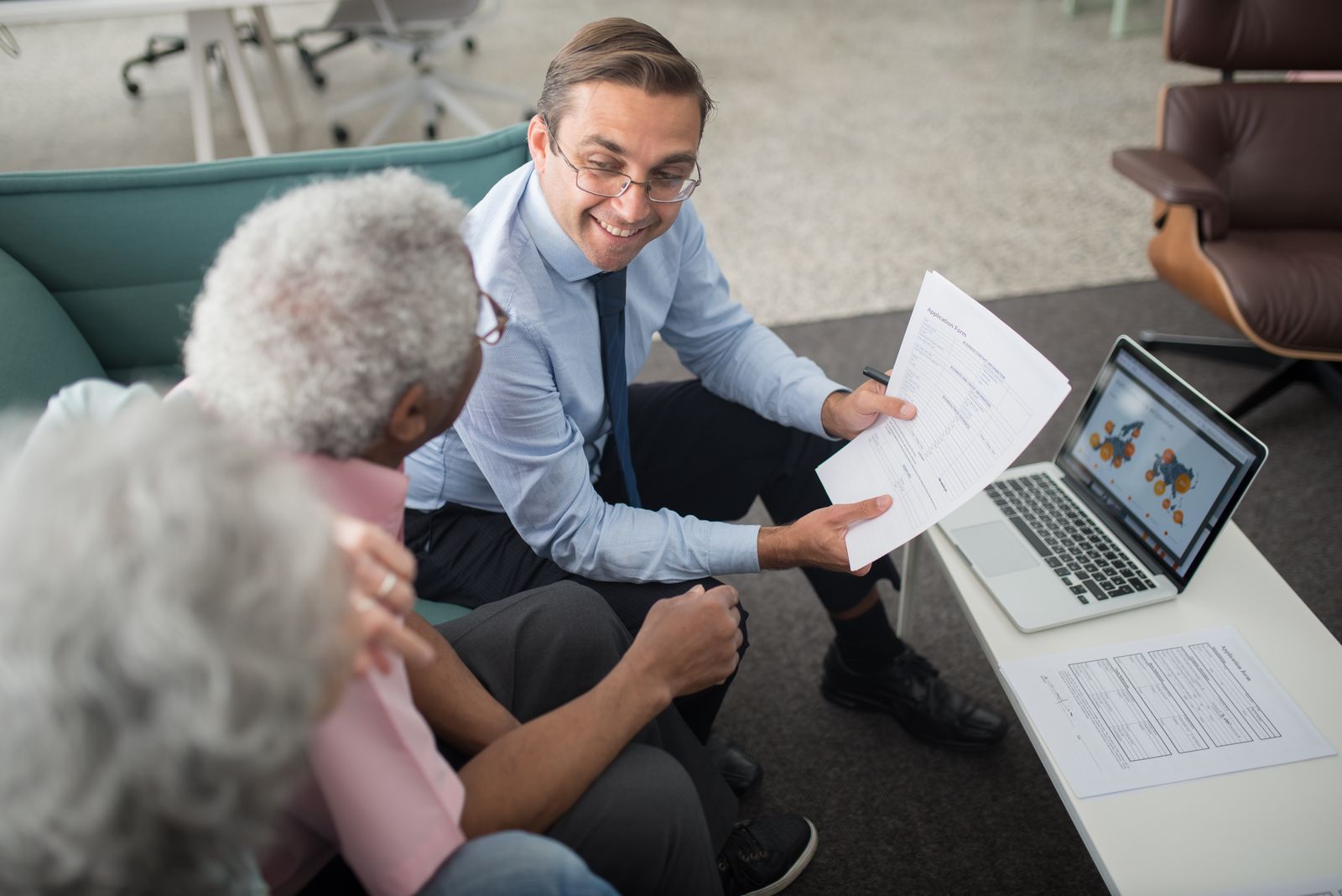 An adviser going through documents with an older couple in a bright office
