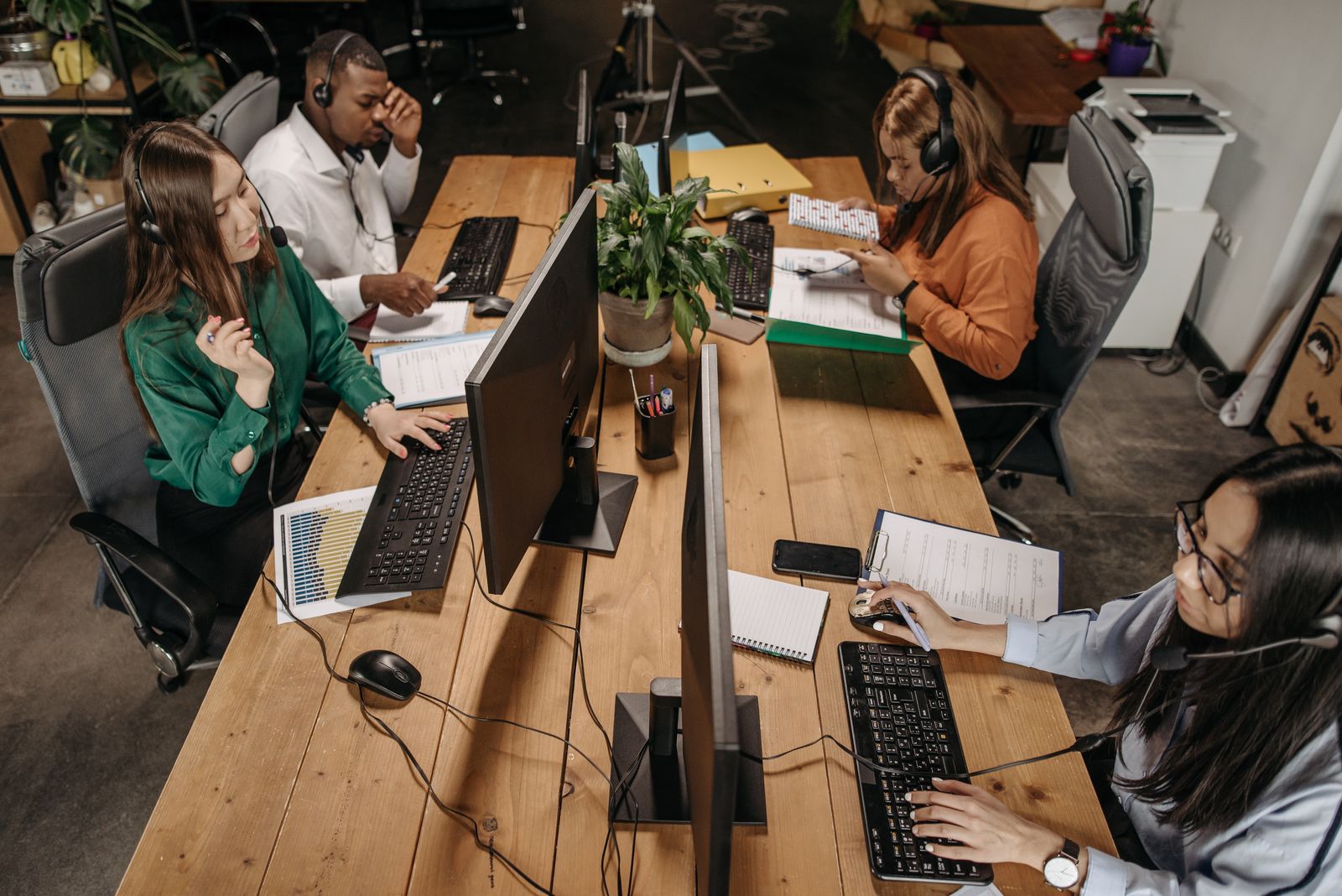 An open-plan office with people working at long desks with laptops and screens