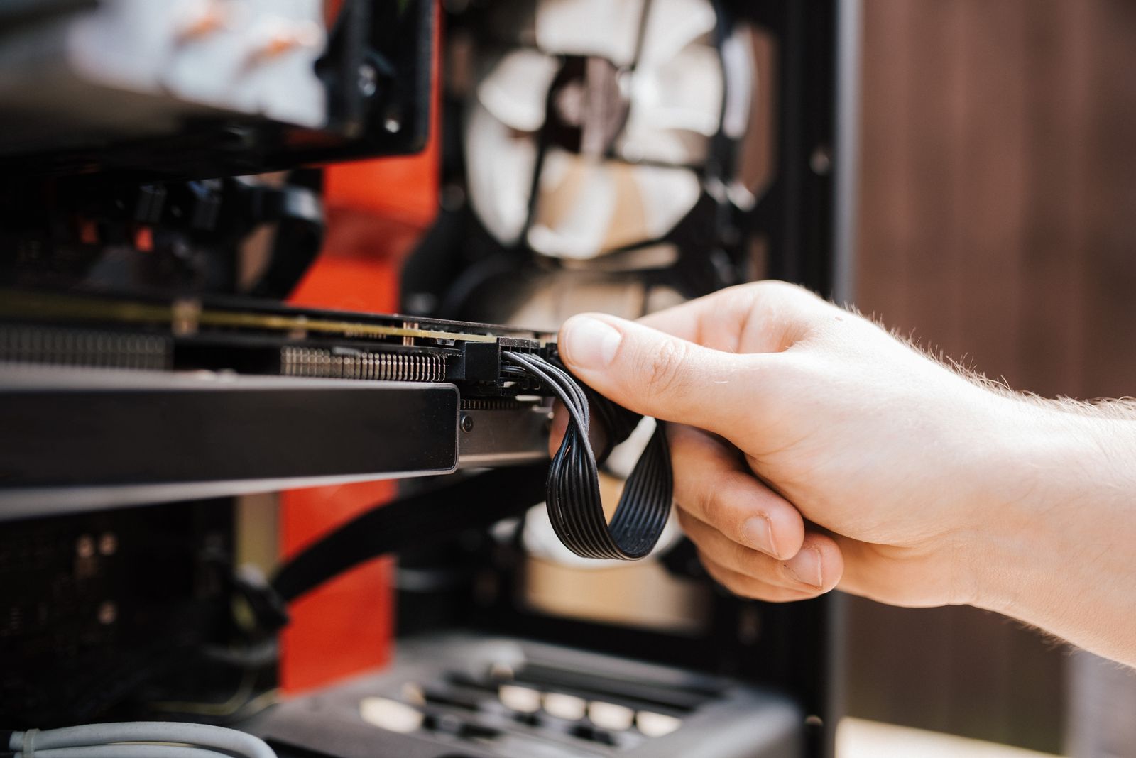 A hand fitting a cable inside an open desktop computer