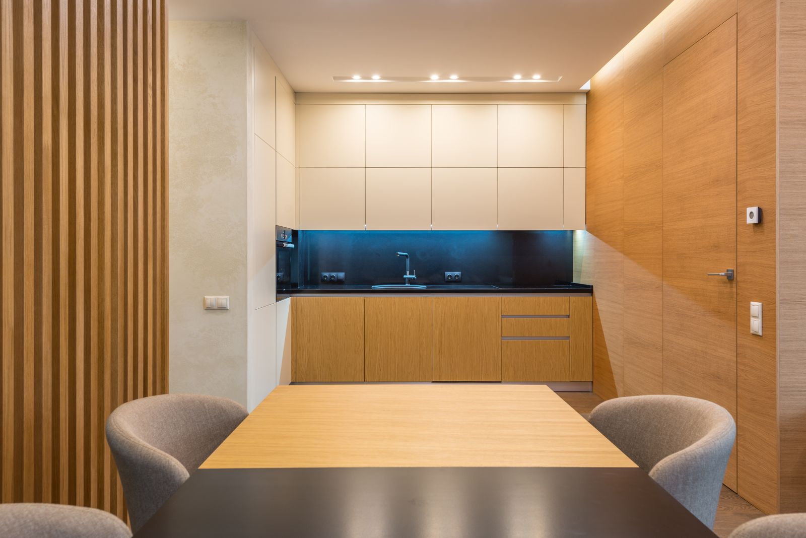 Kitchen-diner with oak cabinets, a long timber table and grey upholstered chairs