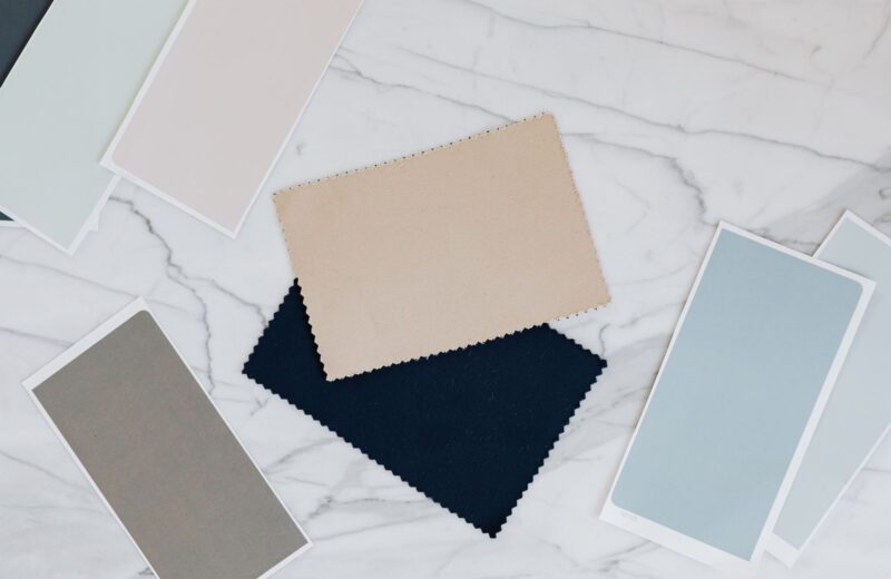 Fabric and colour samples in neutral tones and navy laid out on a white marble table