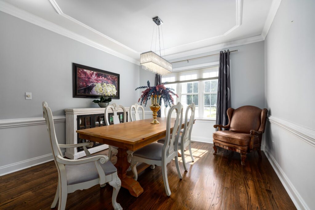 A bright dining room with a wooden table, vintage chairs and a chandelier