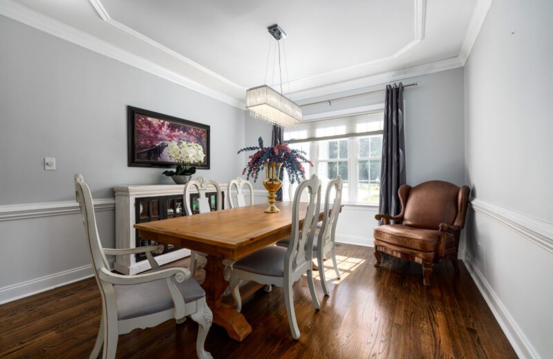 A bright dining room with a wooden table, vintage chairs and a chandelier