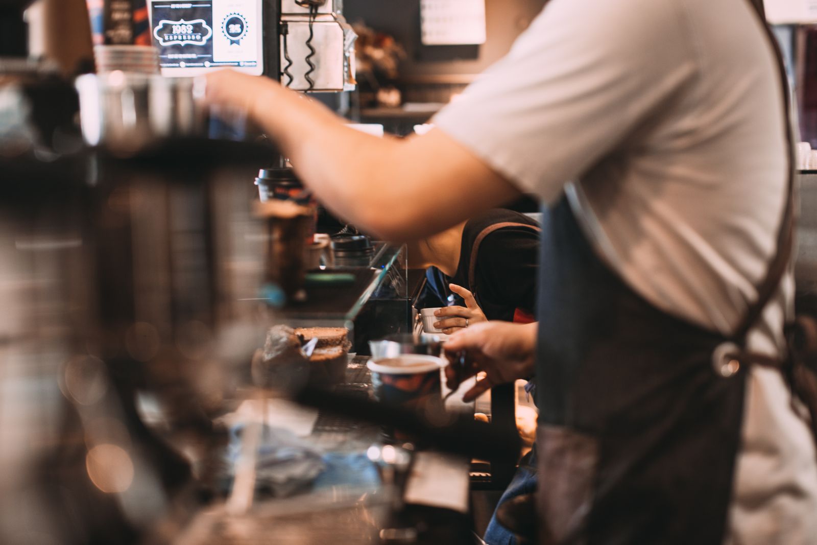 A barista making coffee behind a cafe counter