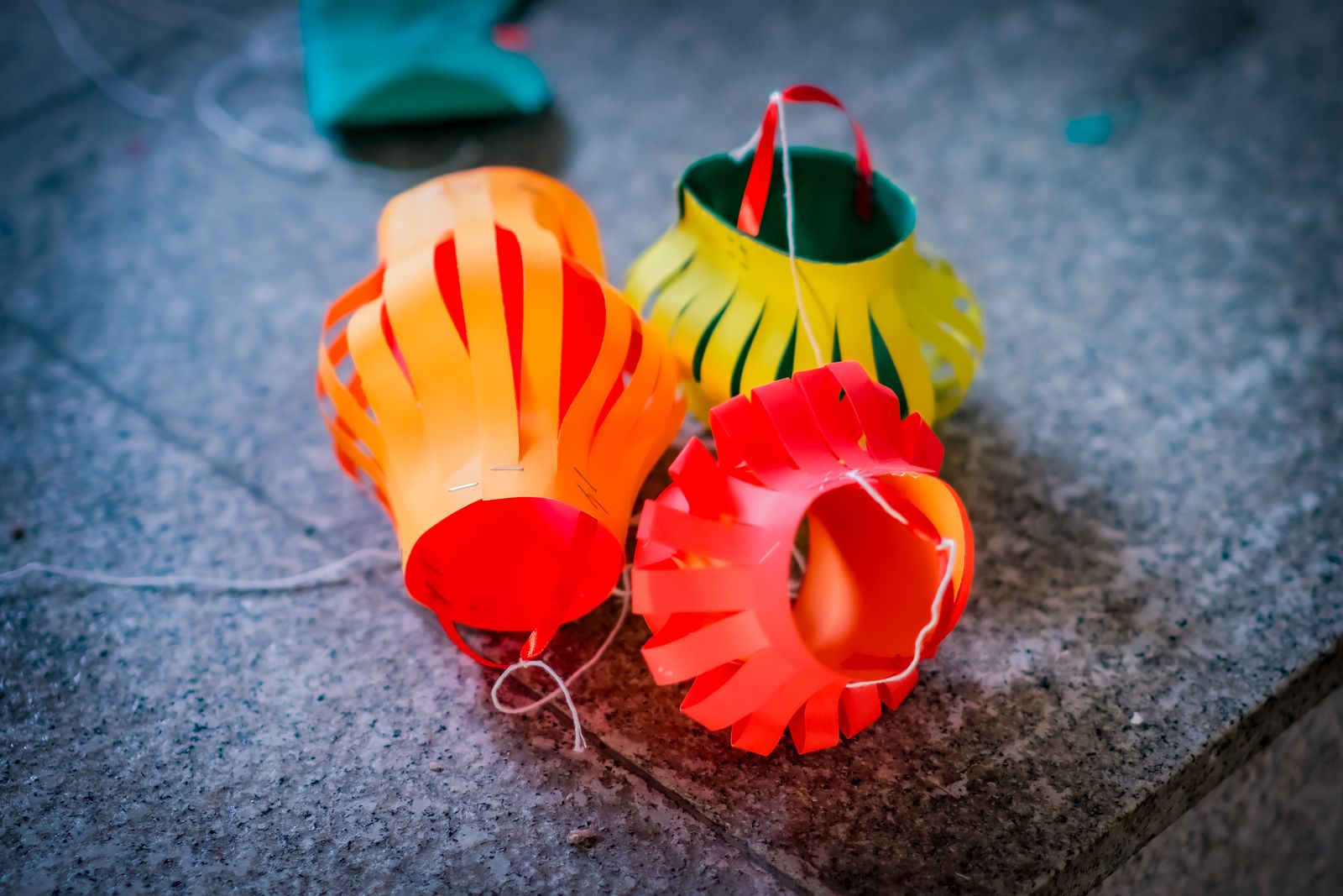 Homemade paper lanterns in orange and yellow on a stone floor