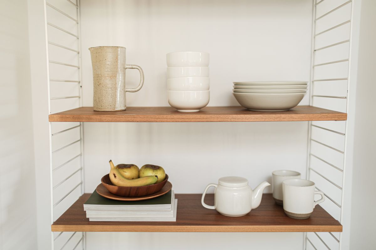 White plates, bowls, a jug and cups on two wooden shelves