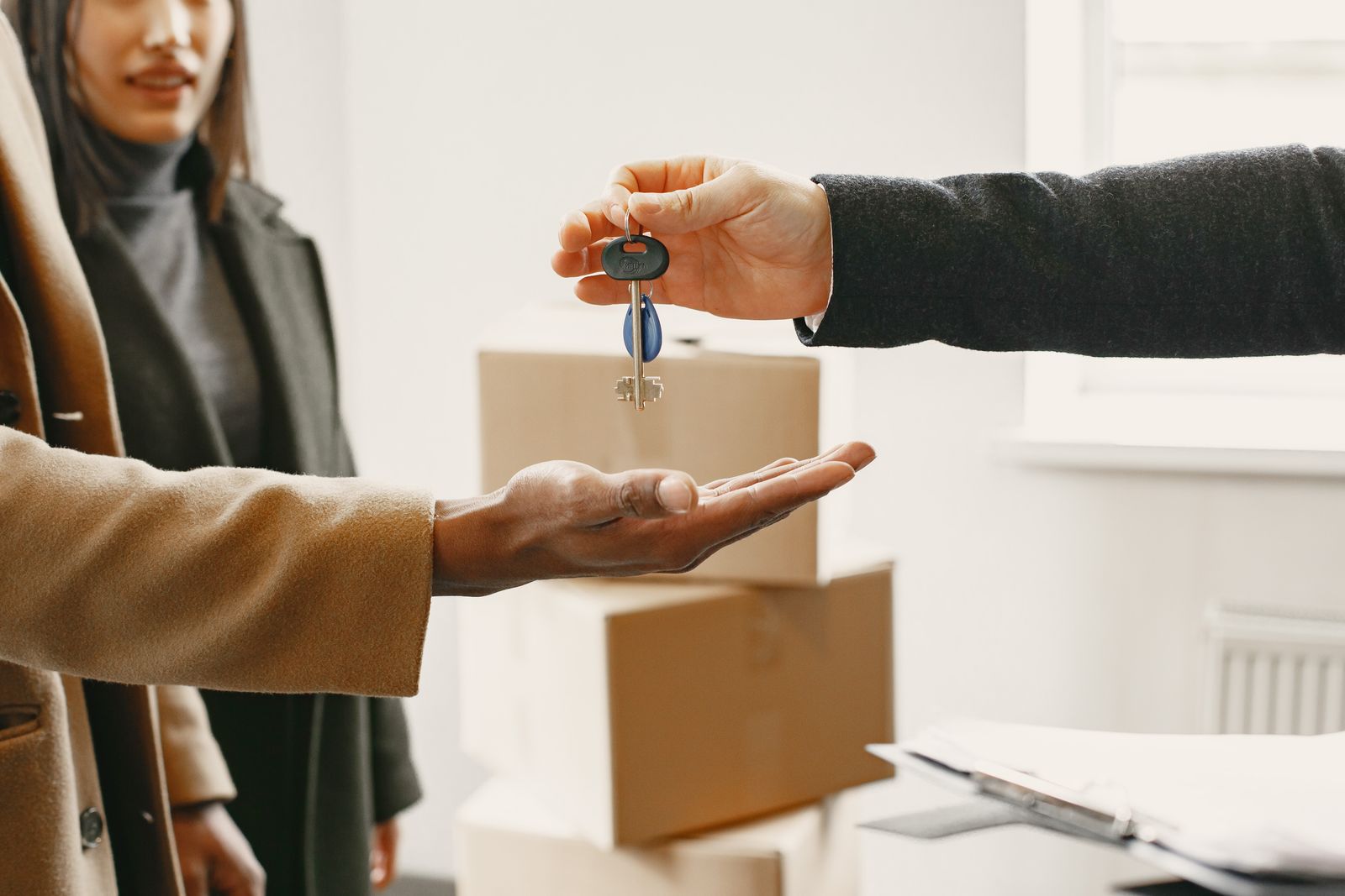 A set of keys handed over above a moving box in a bright new home