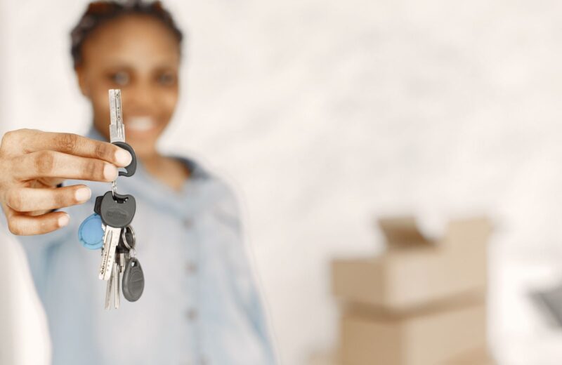 A hand holding a set of house keys in front of moving boxes