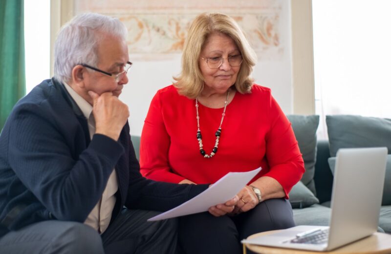 An older couple reading a document together on a sofa