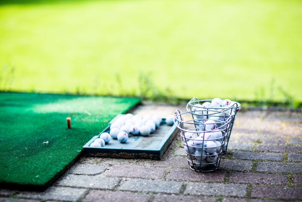 A tray of practice balls on a hitting mat at an outdoor range