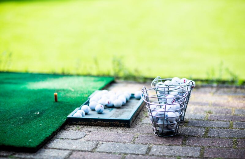 A tray of practice balls on a hitting mat at an outdoor range