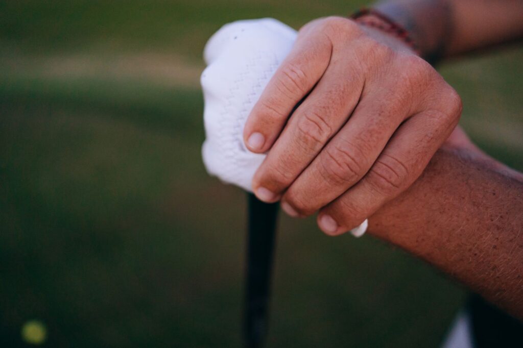 Close-up of two hands holding a golf grip, one in a white glove