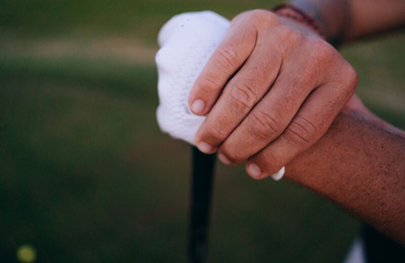 Close-up of two hands holding a golf grip, one in a white glove