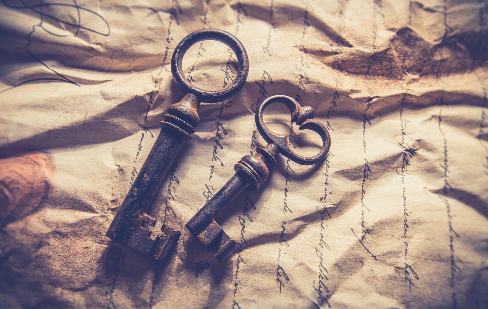 Two old iron keys lying on crumpled handwritten paper