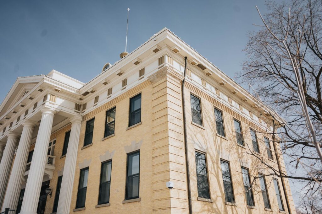 A historic county courthouse with white columns under a blue sky