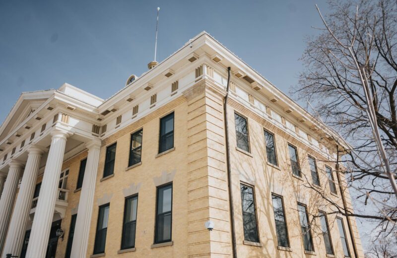 A historic county courthouse with white columns under a blue sky