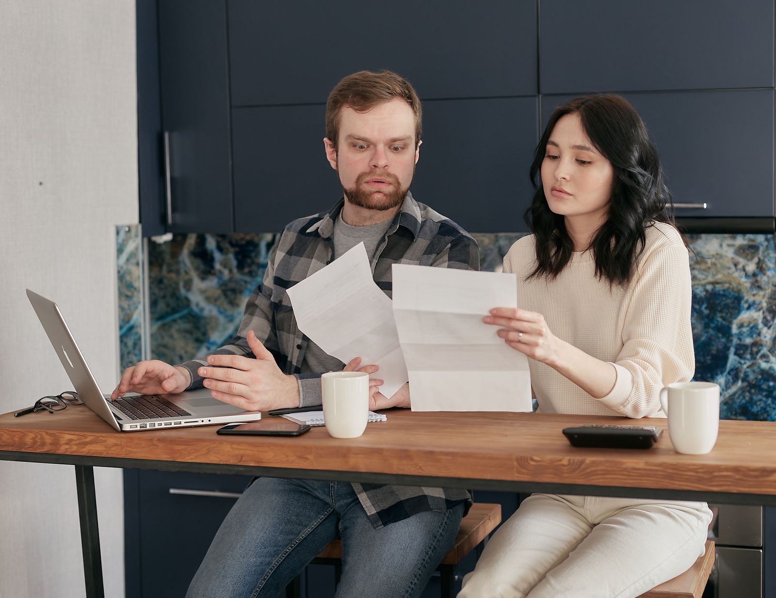 A couple reading letters and bank papers together at a kitchen table