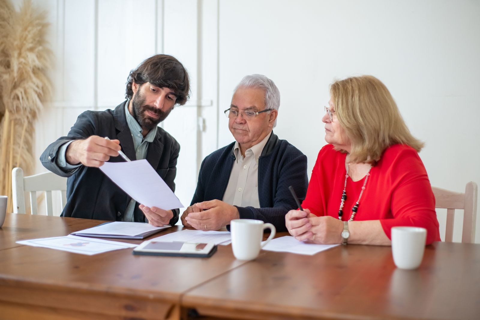An older couple going through documents with an adviser at a wooden table