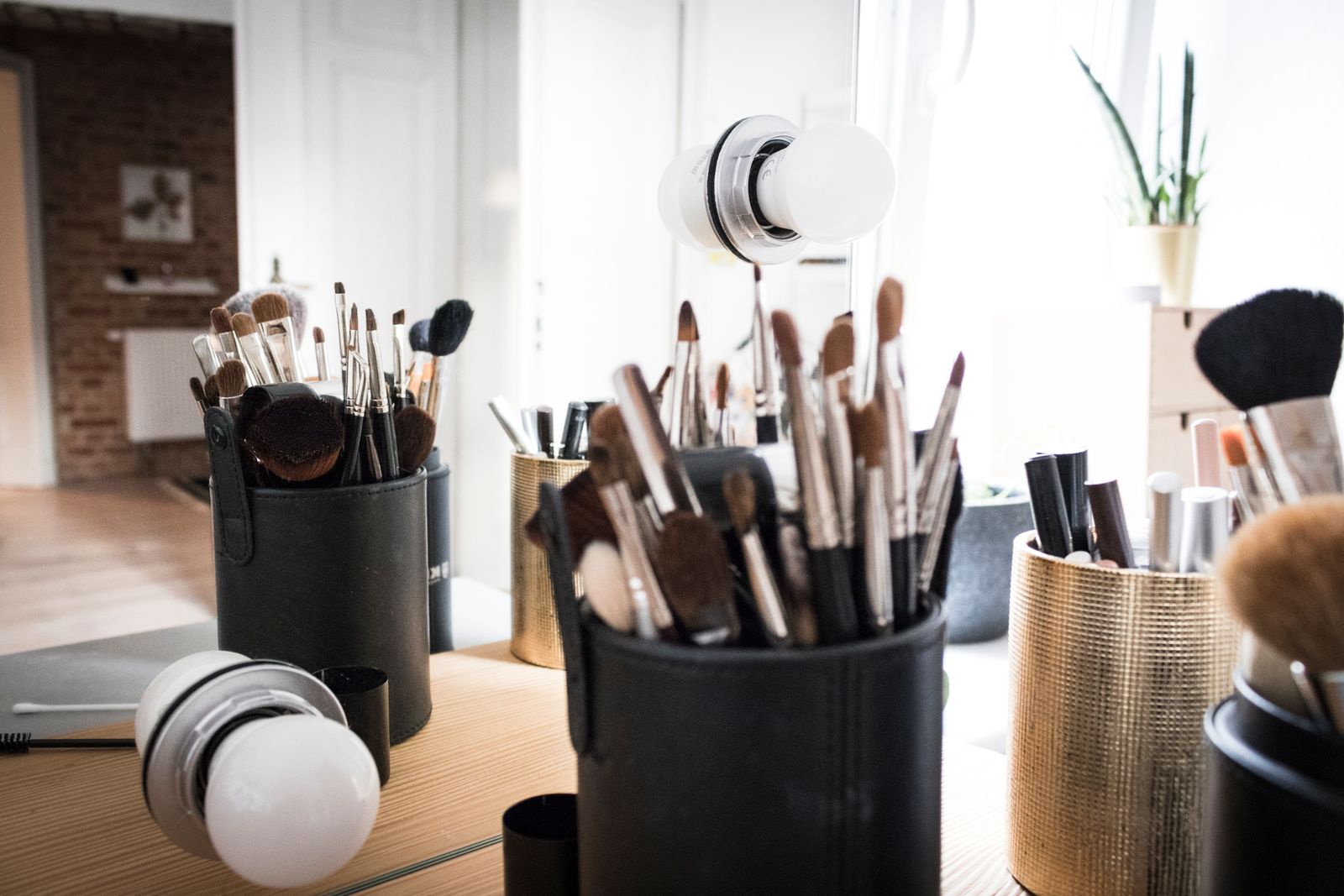 Makeup brushes standing in holders on a vanity table
