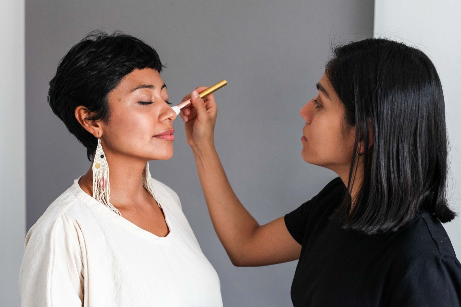 A makeup artist applies makeup to a client in the studio
