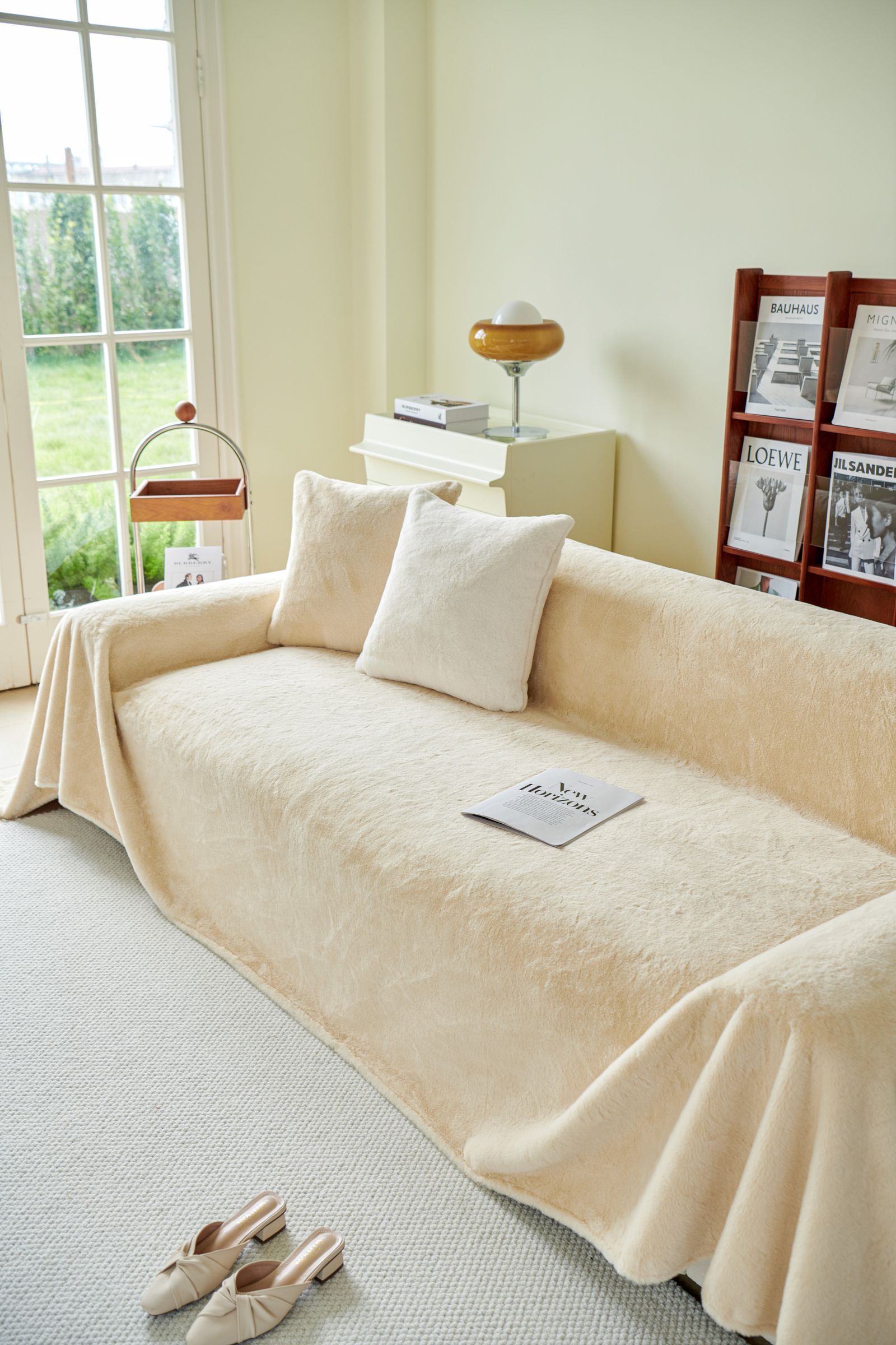 A cream sofa with soft cushions and a throw in a sunlit room