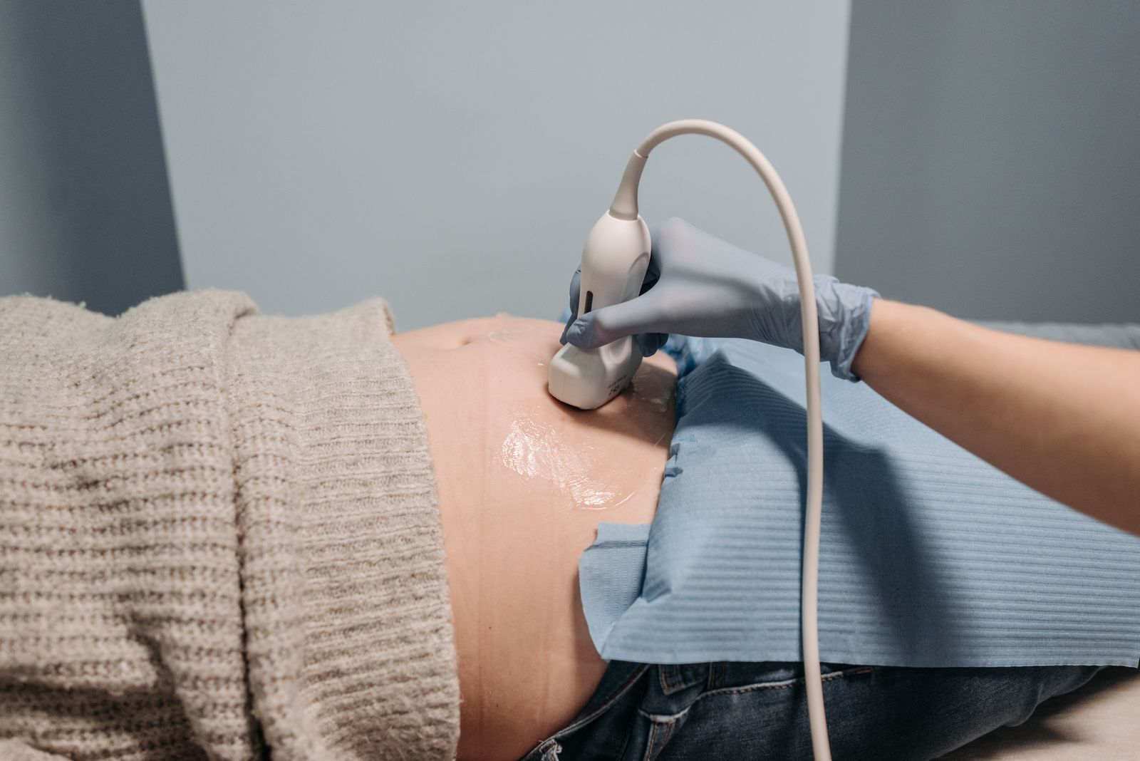 An ultrasound scan on a pregnant belly, the probe held by a sonographer