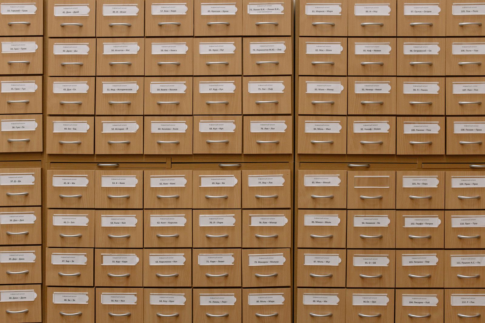 Rows of wooden archive drawers with paper labels