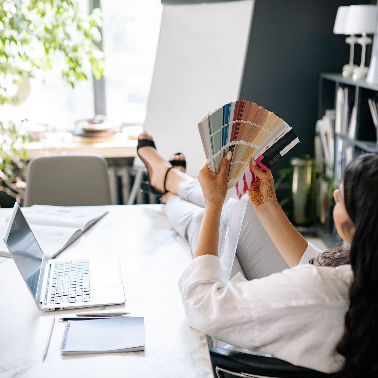 A designer leaning back at a white desk, fanning out a deck of colour swatches