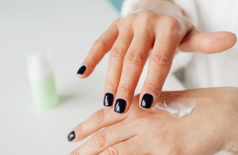 Hands with dark nails rubbing in hand cream