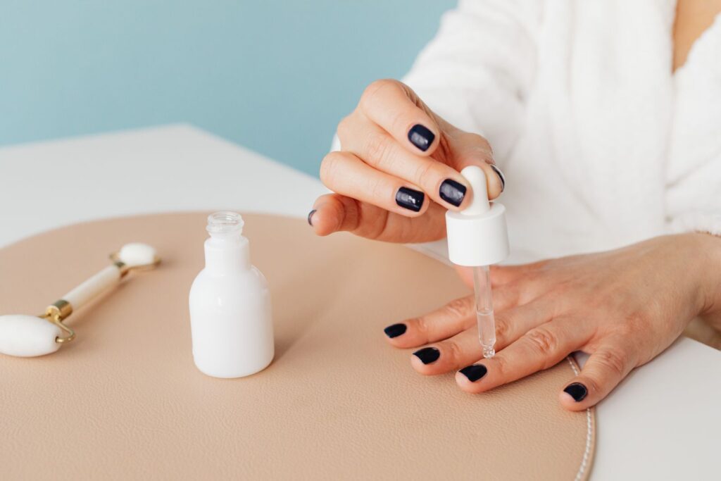 A drop of cuticle oil applied to dark painted nails